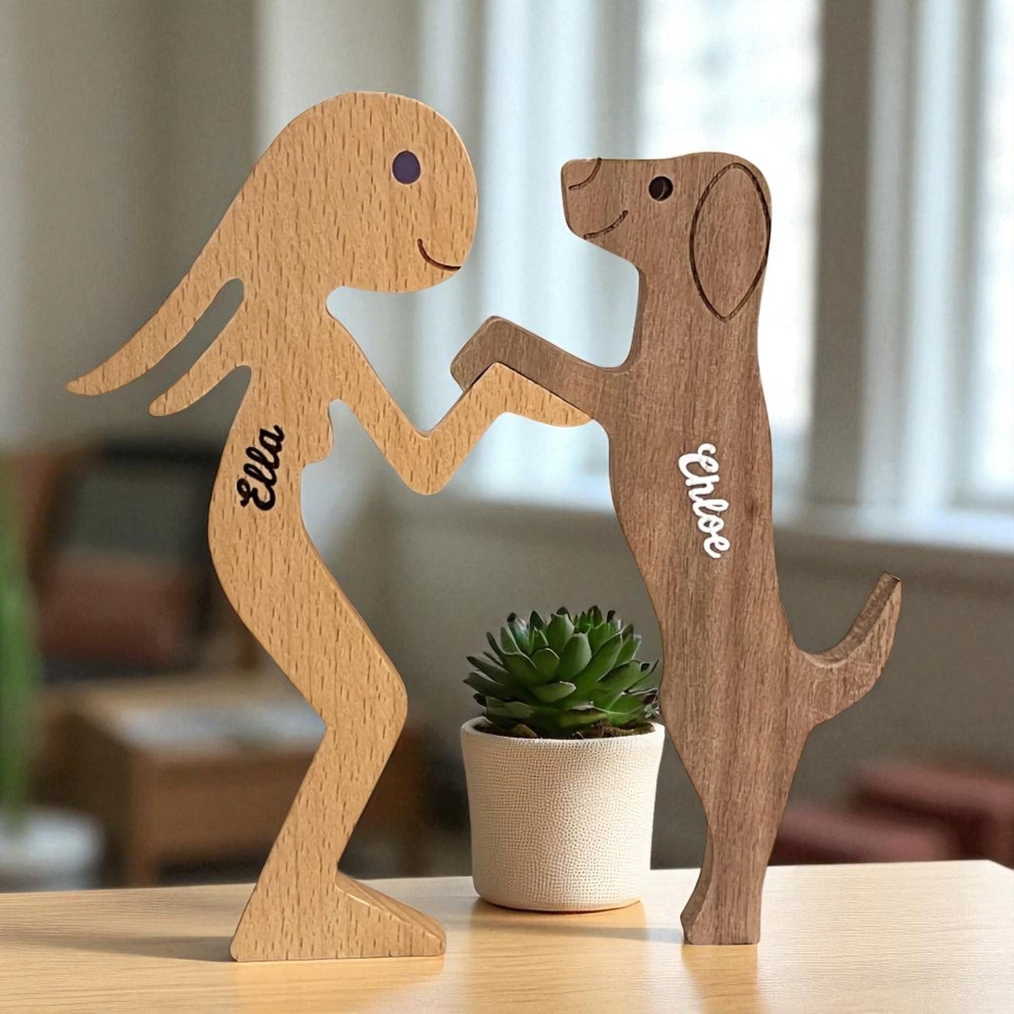 Close up of custom engraved names on wooden dog and owner puzzle, placed on a table with a plant.