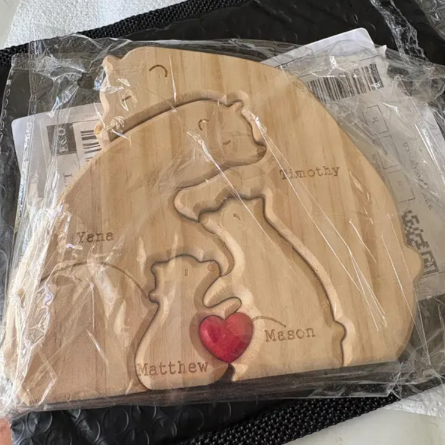 Wooden Bear Family Puzzle with engraved names for the four family members placed on a black envelope.