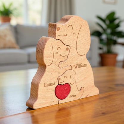 Wooden family puzzle of dog figurines with three pieces and a red heart, standing on a table with plants in the background, All names are custom engraved for the family member names.