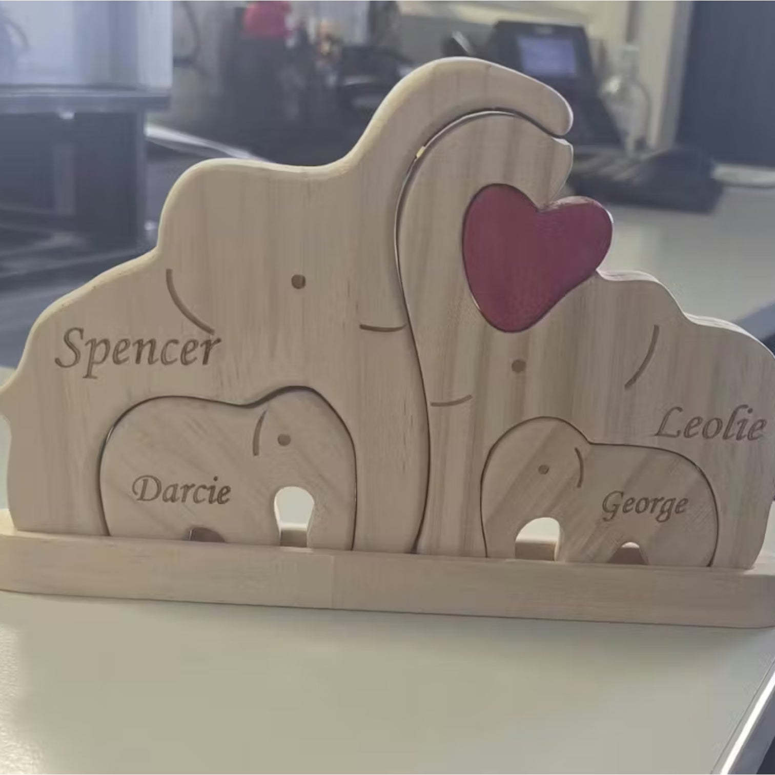 Wood Elephant Family Puzzle with family members names engraved in it, on a white table top.