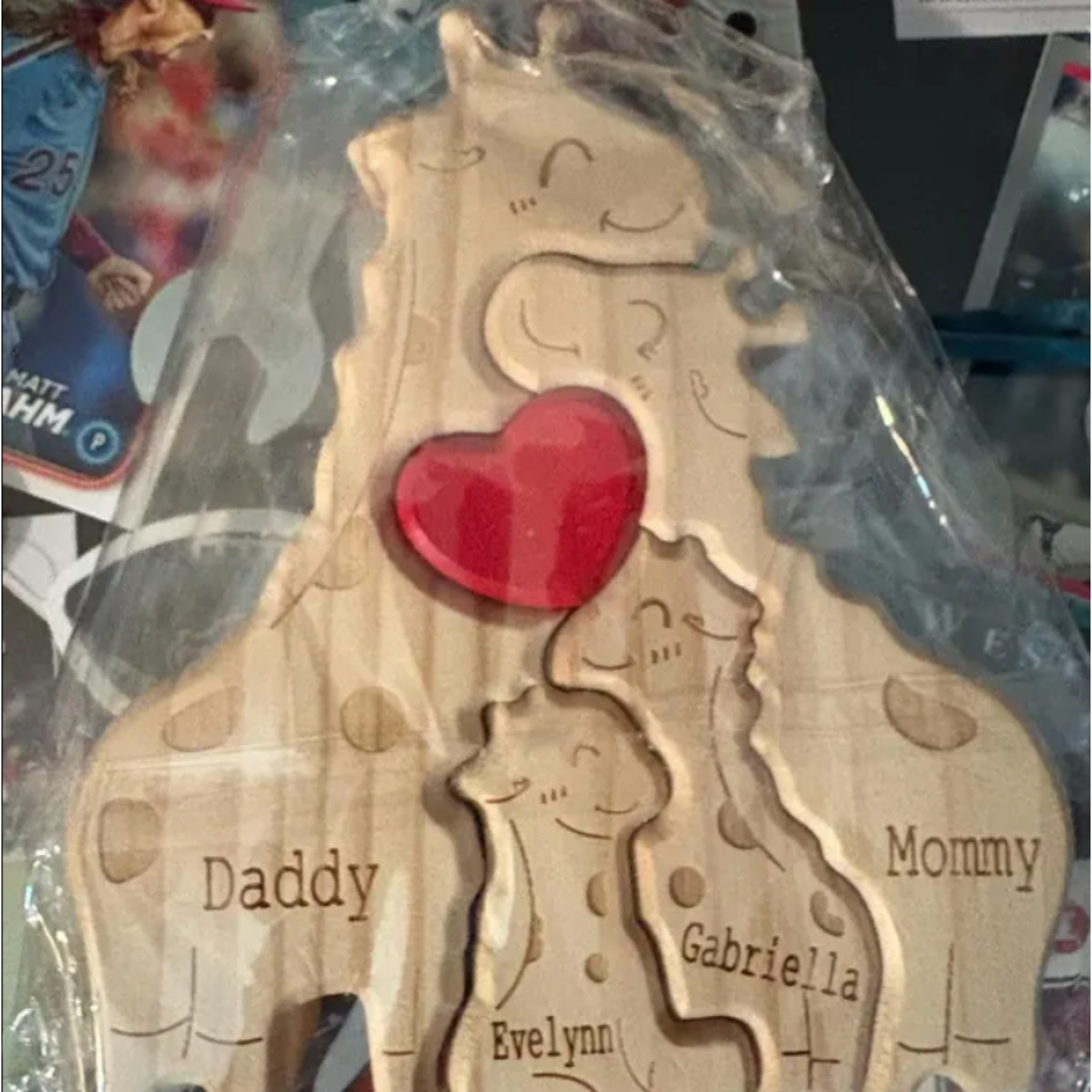 Personalised Wood Giraffe Family Puzzle with engraved names of the family members, handmade gift on a black table.