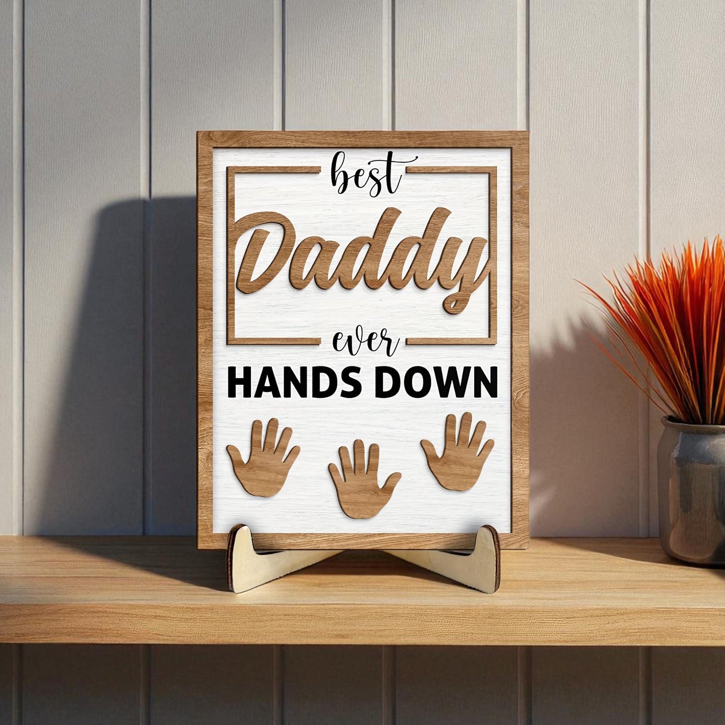 Decorative sign with 'best Daddy ever HANDS DOWN' text on a wooden stand. Handmade dad handprint frame showing three kids with engraving