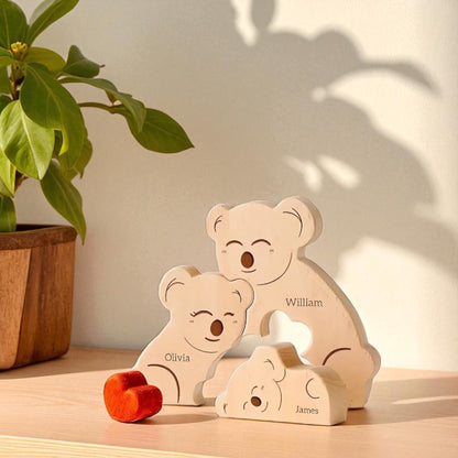 Handmade koala family ornament for trio of family members with engraving with a plant in the background.