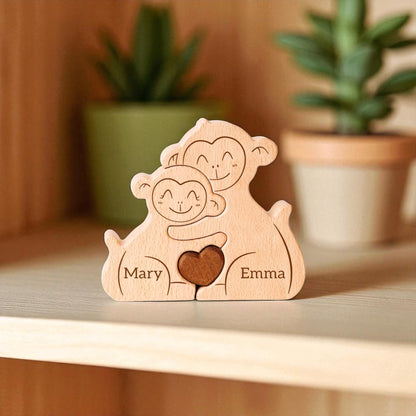 Wooden figurine of two monkeys holding a heart with engraved names, placed on a wooden surface with plants in the background.