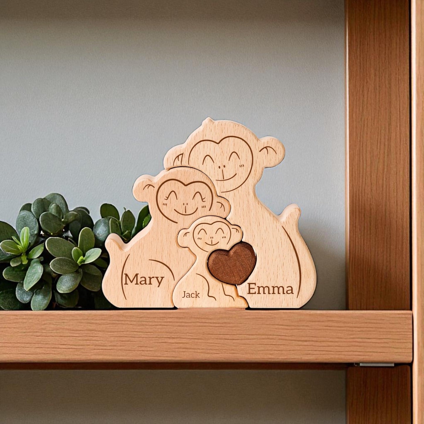 Personalised monkey family wooden puzzle for 3 people with custom engraved names on a shelf with a plant.