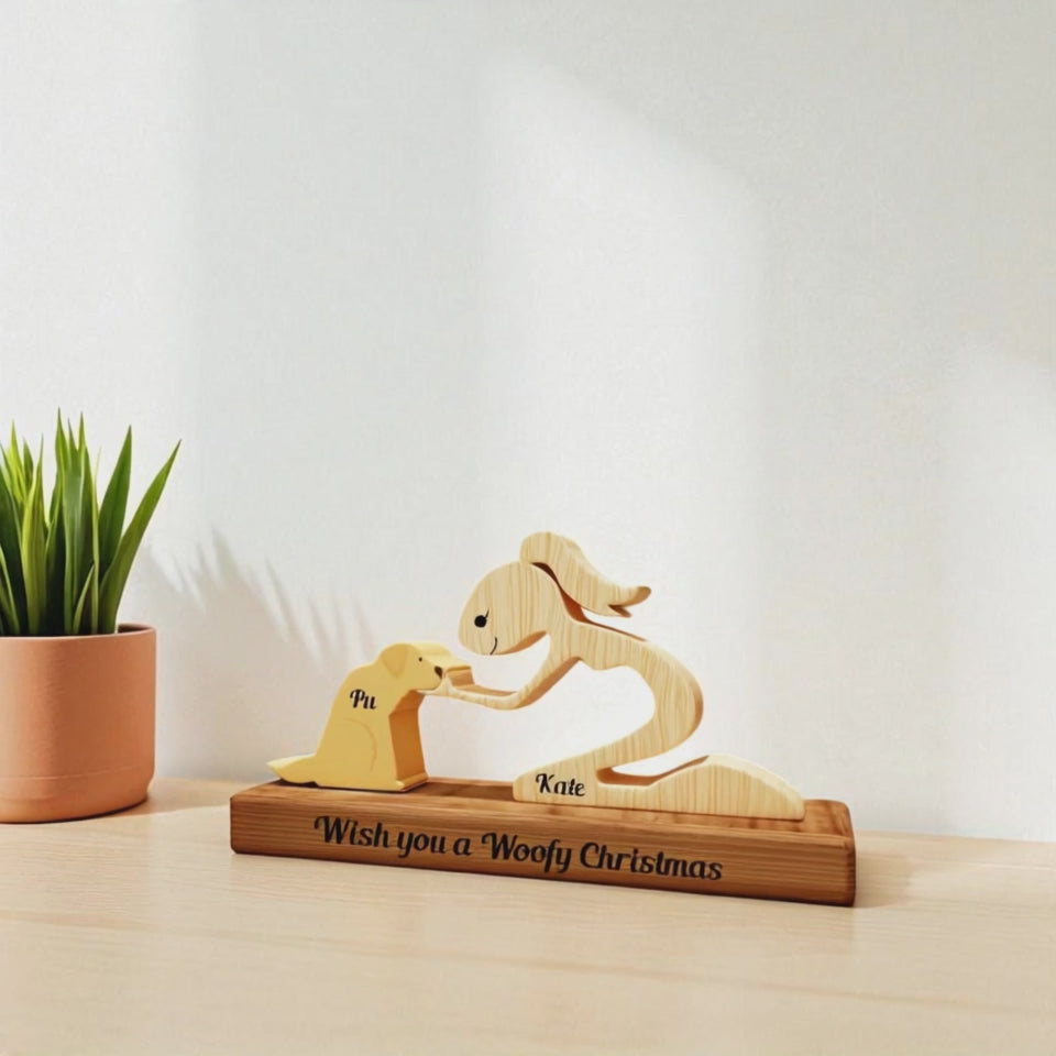 Wooden sculpture of a woman and a dog on a stand with 'Wish you a Woofy Christmas' text, next to a plant.
